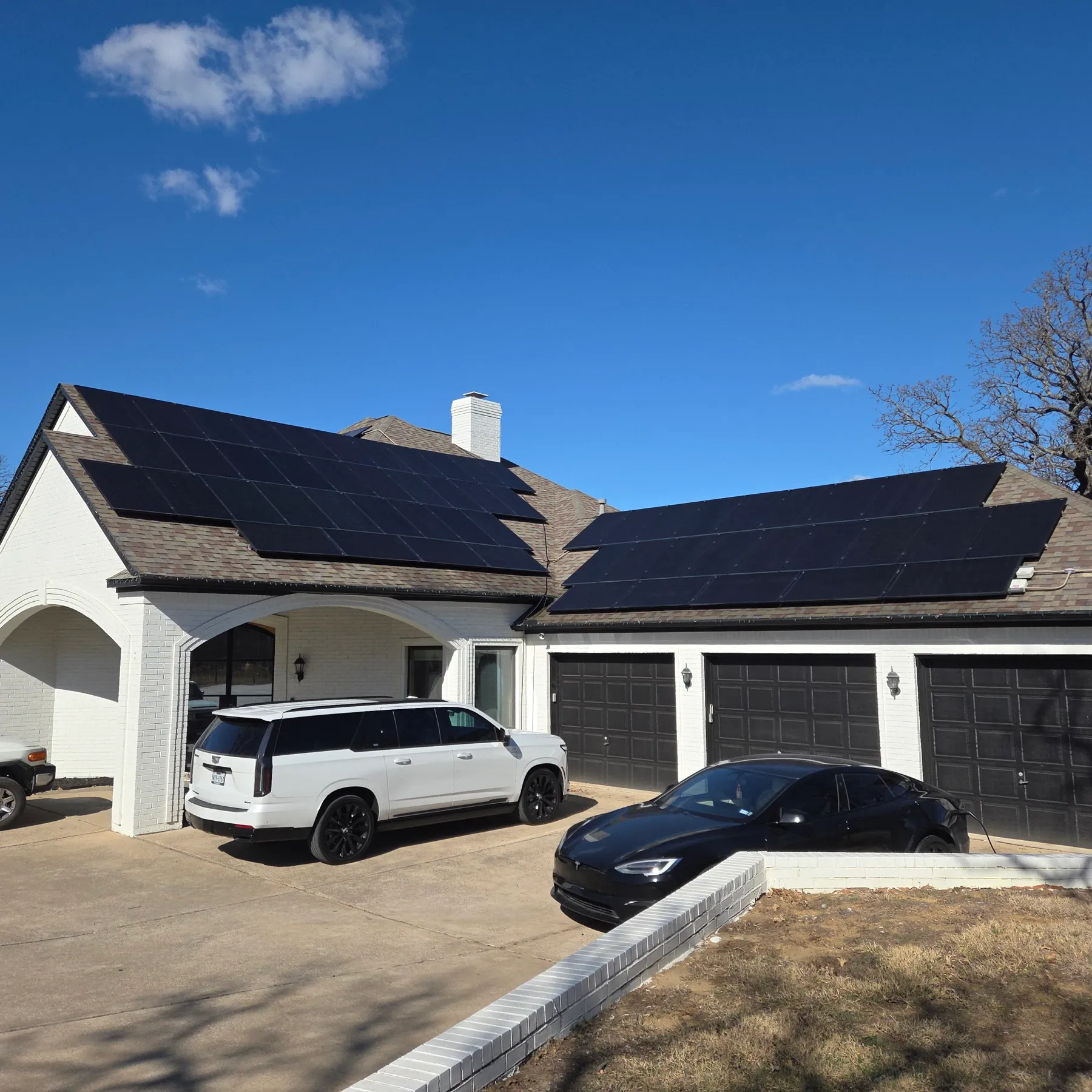 A white brick North Texas home with black solar panels across the front and side roof